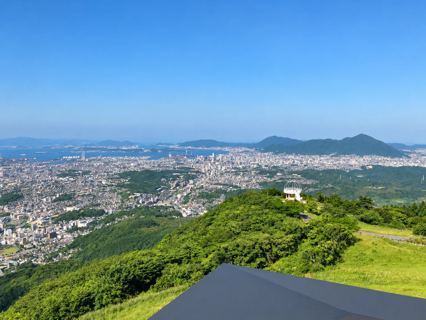 日中の皿倉山から見渡す北九州の街並みと山の緑