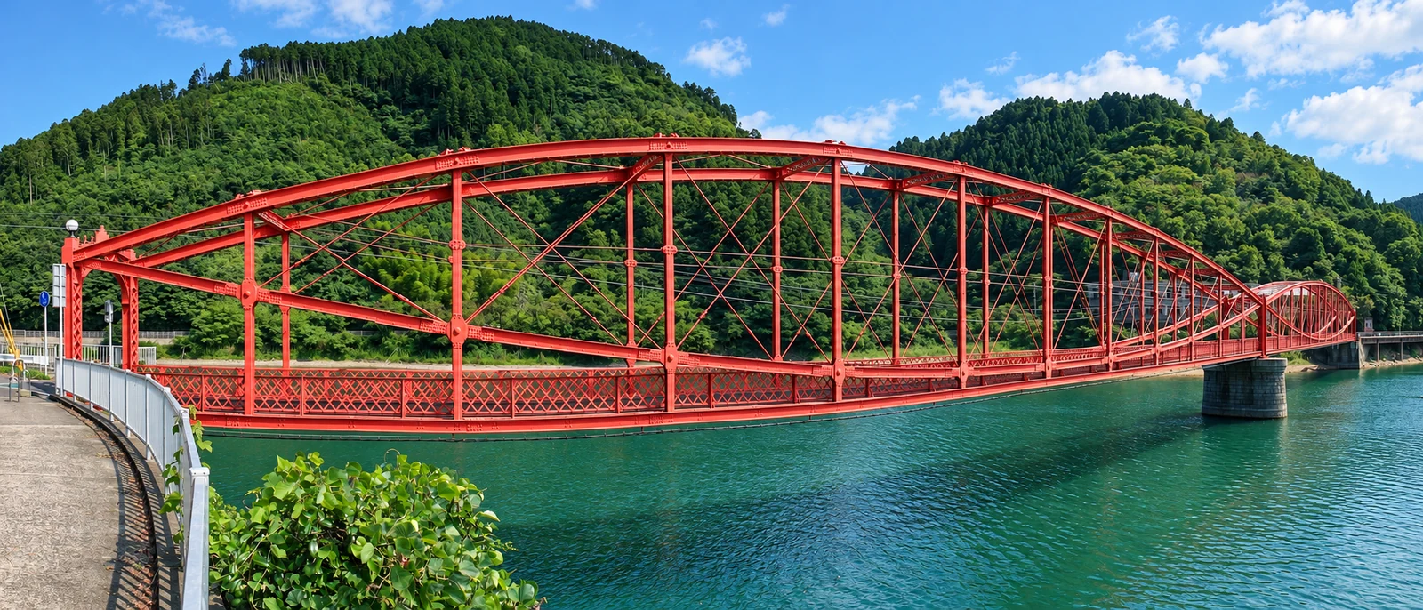 水面と山林を背景に、二連のレンズ形を描く赤い南河内橋